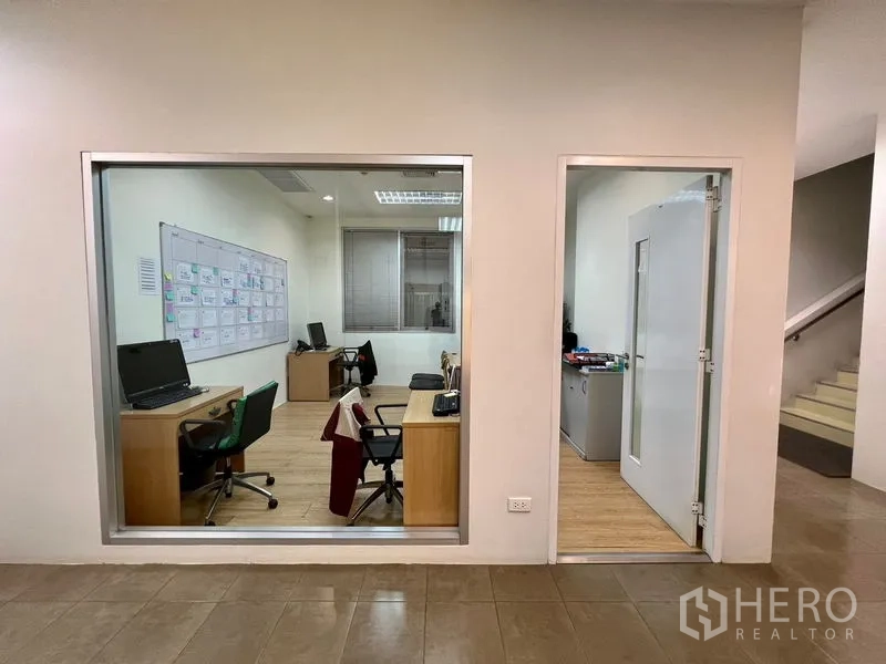 Office Space for rent in Bueng Kum, Bangkok - View into an administrative office through an interior window, showing desks, chairs and equipment.