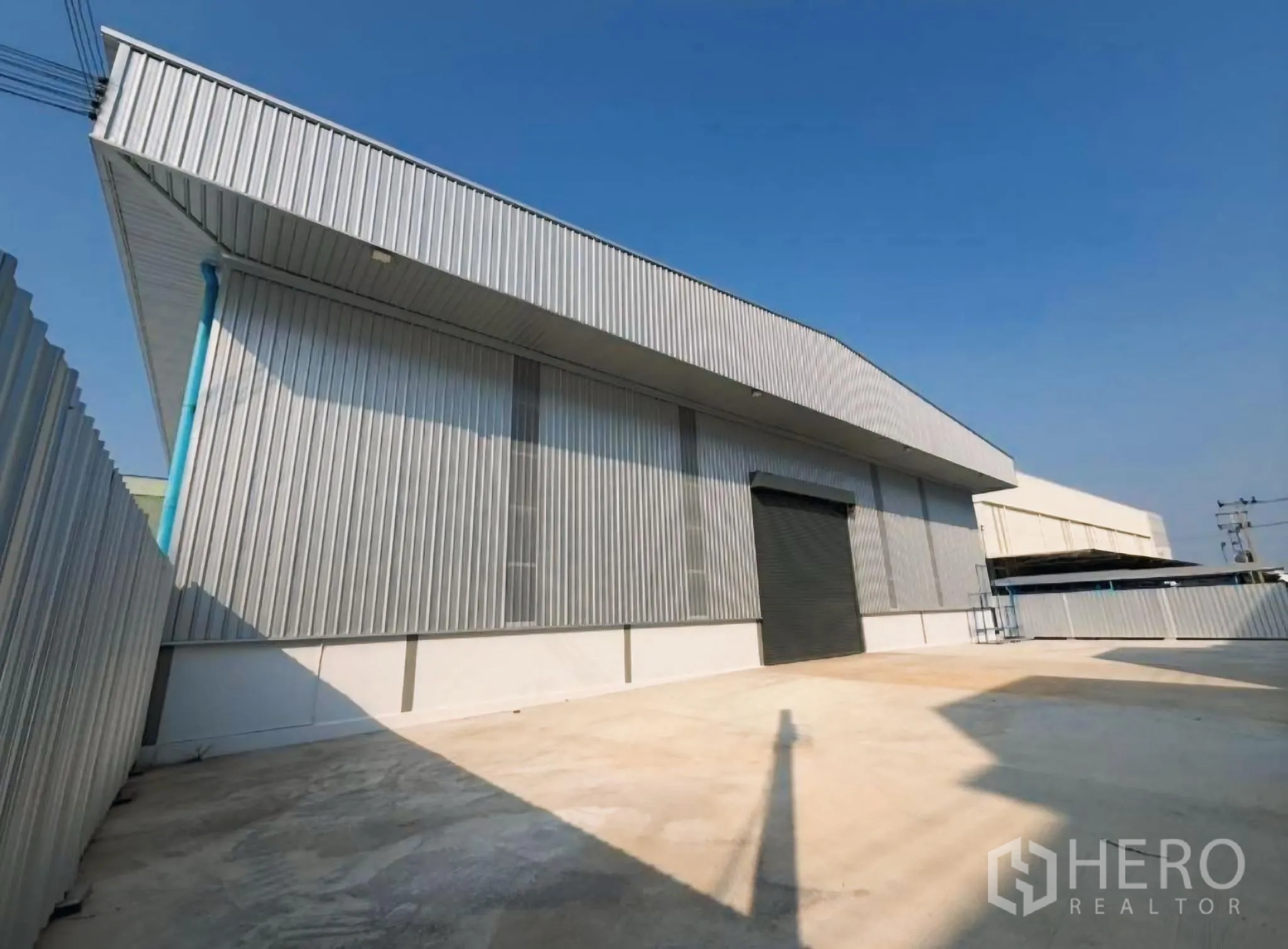 Warehouse for rent in Bang Khun Thian, Bangkok - Warehouse exterior with roller shutter and wide paved loading yard.