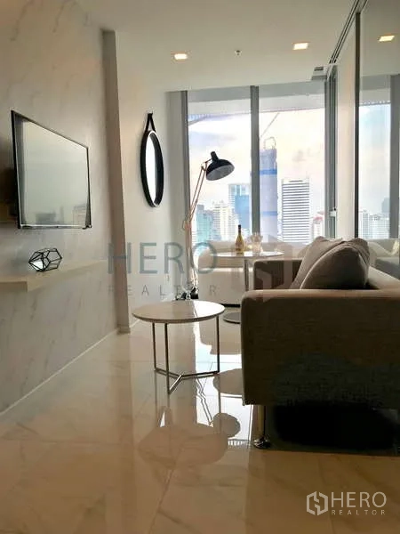 คอนโด ให้เช่า - พื้นที่นั่งเล่นโอเพ่นแพลน โซฟา ทีวี และห้องนอนกั้นกระจก วิวเมือง