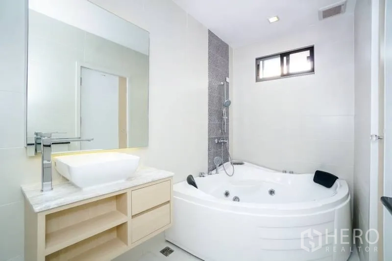 บ้าน ให้เช่าหรือขายในLat Krabang, Bangkok - ห้องน้ำโทนขาวมีอ่างจากุซซี่มุมห้อง ฝักบัว และเคาน์เตอร์อ่างล้างหน้า