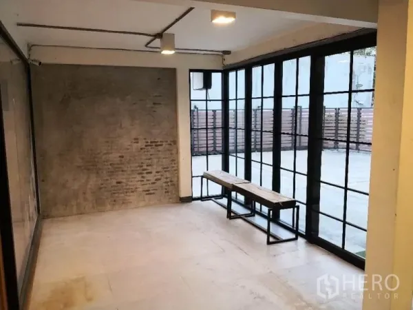 พื้นที่ขายปลีก ให้เช่าในKhlong Toei, Bangkok - มุมโชว์รูมพร้อมผนังกระจกเต็มบาน ผนังคอนกรีตเปลือย และม้านั่งหันออกลาน.