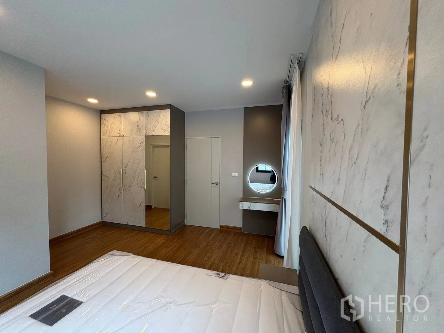 Detached House for rent in Bang Phli, Samut Prakan - Bedroom angle showing marble-look wardrobe, dressing table, sheer curtains and recessed lighting.