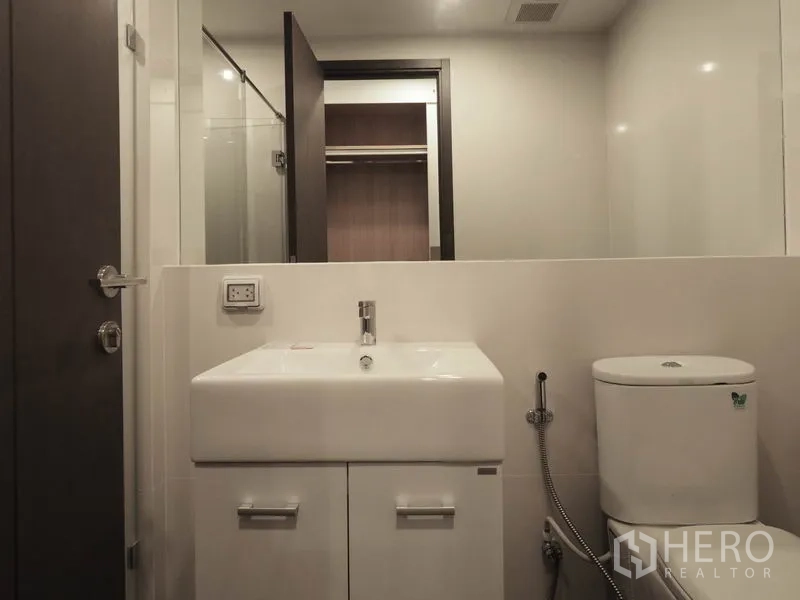 Condominium for rent in Sathon, Bangkok - Second bathroom with square vanity, toilet and glass-door shower.
