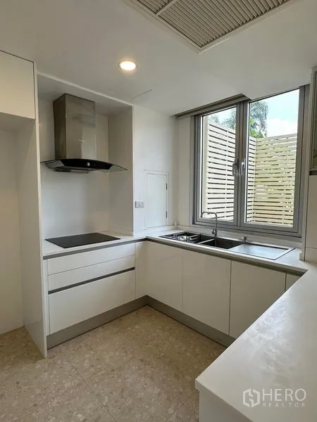 Townhouse for sale in Yan Nawa, Bangkok - Compact L-shaped kitchen with cooktop, hood and window with privacy screen