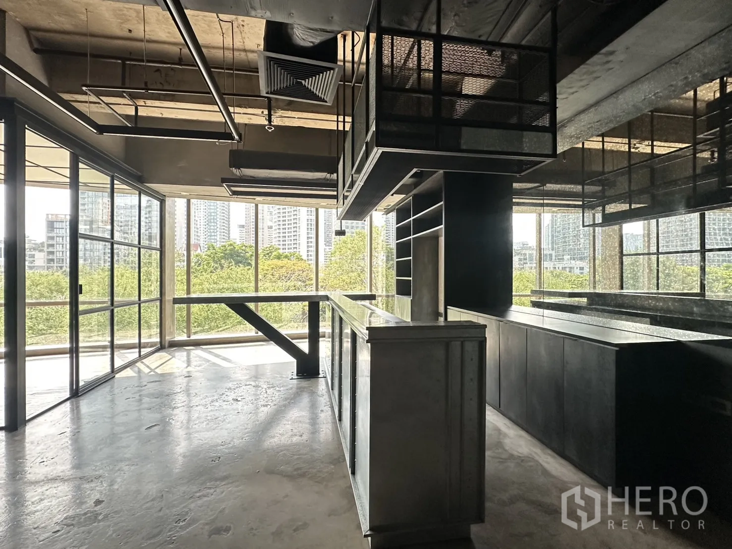 ออฟฟิศ for rent in Pathum Wan, Bangkok - โถงทำงานแปลนเปิดโล่ง มีเคาน์เตอร์บิวท์อิน ชั้นเก็บของ และหน้าต่างพาโนรามาเหนือเรือนยอดไม้