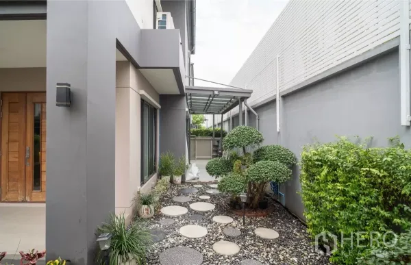 Detached House for rent or sale in Saphan Sung, Bangkok - Side yard featuring a pebble pathway, manicured shrubs and a glass canopy.