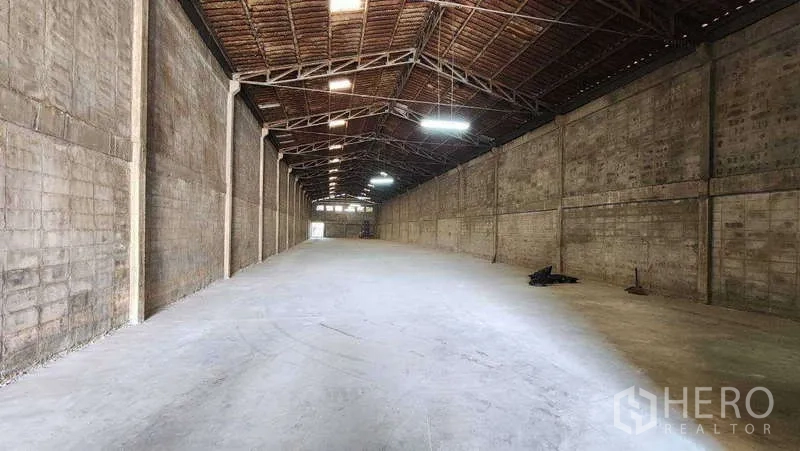 Warehouse for rent in Nong Khaem, Bangkok - Spacious warehouse interior with a high steel-truss roof and smooth concrete floor.