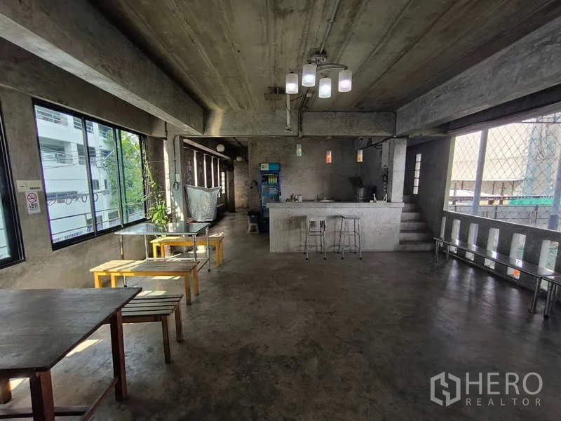 Warehouse for rent in Huai Khwang, Bangkok - Multipurpose hall with bar counter, stools and tables in an industrial setting.