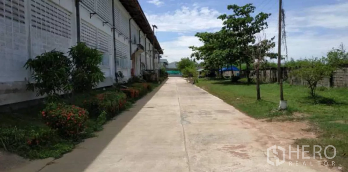 Factory for rent in Bang Pakong, Chachoengsao - Side walkway along a factory wall with garden beds and open green space for easy truck access.