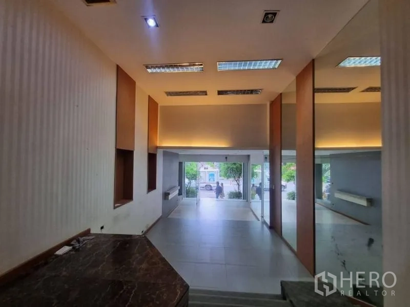 店屋 出租在Watthana, Bangkok - 从抬高区域望向玻璃入口，可见镜面与顶灯。