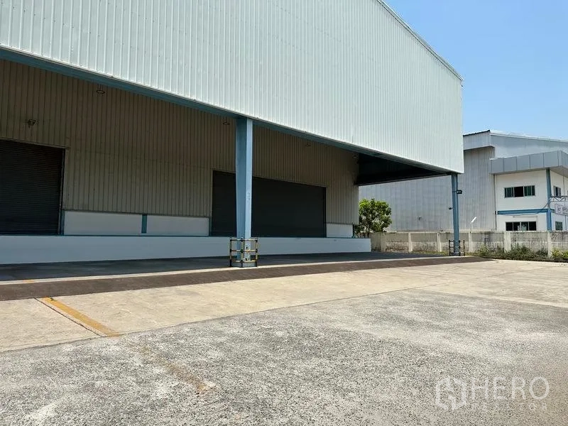 Warehouse for rent in Bang Phli, Samut Prakan - Angled view of the loading platform with multiple dock doors and a spacious concrete yard for truck maneuvering.