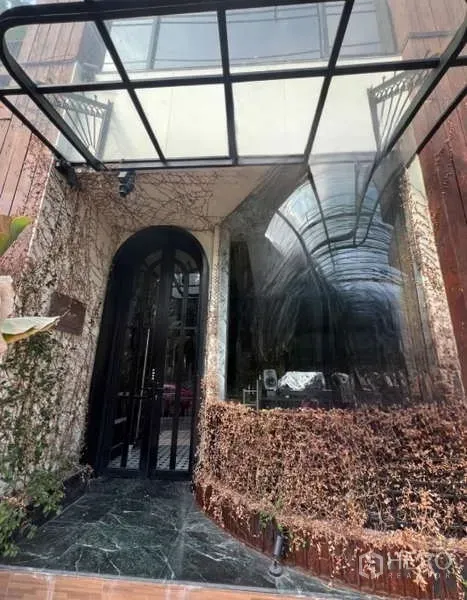 พื้นที่ขายปลีก ให้เช่าในWatthana, Bangkok - มุมใกล้ของทางเข้าโค้ง กันสาดกระจก หน้าต่างโค้ง และผนังปกคลุมเถาวัลย์