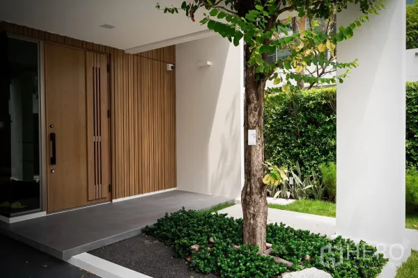 Detached House for rent in Saphan Sung, Bangkok - Contemporary house entrance with wood-panel front door and a small garden tree