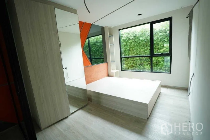 独立商业地产 出租在Bang Na, Bangkok - 采光充足的房间，平台床与橙色特色墙。