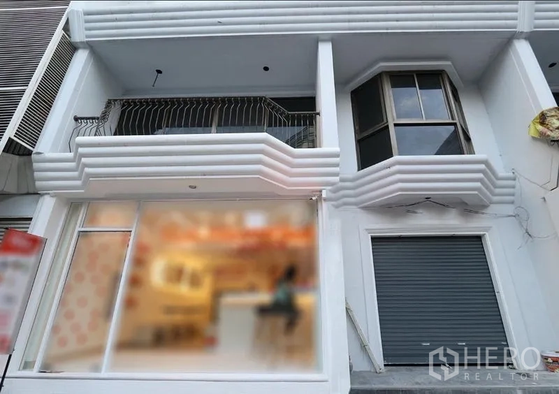 零售空间 出租在Pathum Wan, Bangkok - 一层店面外立面，宽幅玻璃橱窗、阳台与凸窗，配有安全卷帘门