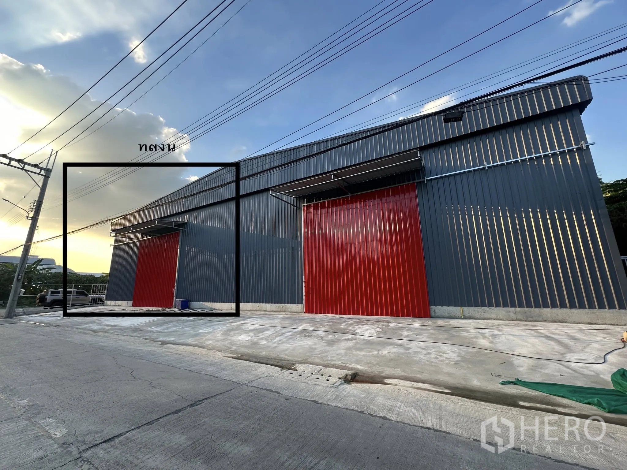 Warehouse for rent in Bang Kapi, Bangkok - Warehouse exterior with wide sliding metal doors and a concrete driveway for loading.