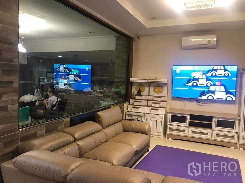 独立式住宅 出租或出售在Prawet, Bangkok - 客厅内设大幅观景窗可见厨房，墙挂电视柜