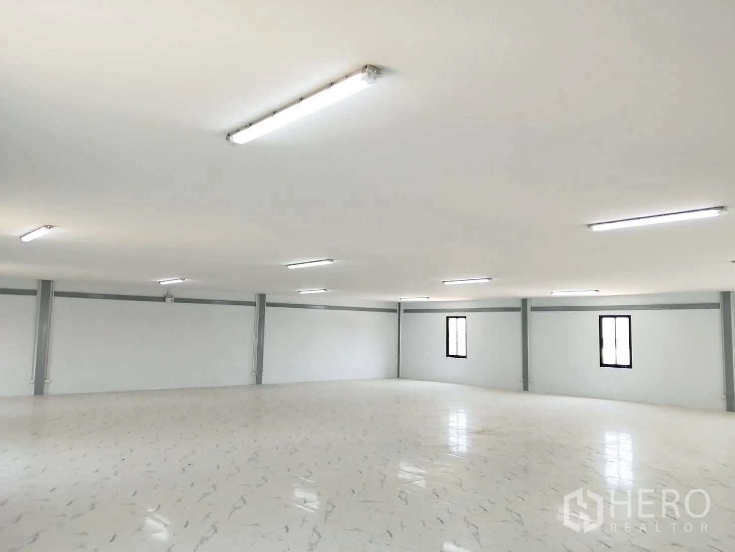 Warehouse for rent in Bang Bo, Samut Prakan - Large office floor with tiled surface, windows, and fluorescent ceiling lights.