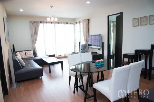 คอนโด ให้เช่าในKhlong Toei, Bangkok - ห้องนั่งเล่นและรับประทานอาหารสว่าง โซฟาหนังเข้ามุม โต๊ะกระจก และผนังกระจกเต็มบานในคอนโดสุขุมวิท