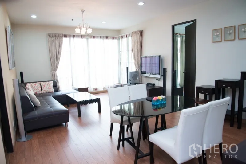 คอนโด ให้เช่าในKhlong Toei, Bangkok - ห้องนั่งเล่นและรับประทานอาหารสว่าง โซฟาหนังเข้ามุม โต๊ะกระจก และผนังกระจกเต็มบานในคอนโดสุขุมวิท