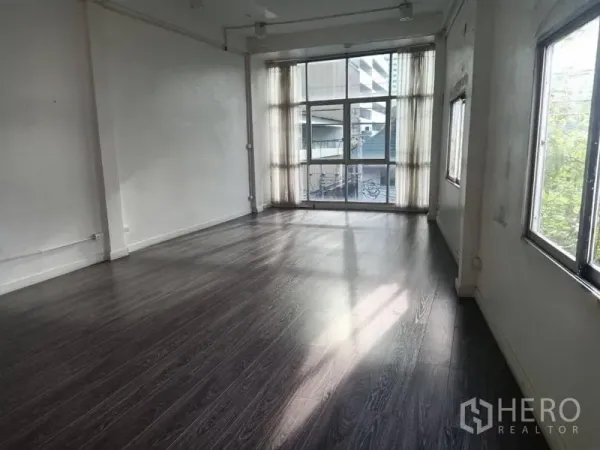 零售空间 出租在Watthana, Bangkok - 采光充足的空置零售空间，深色木地板与落地窗。