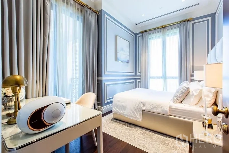 Condominium for sale in Pathum Wan, Bangkok - Bedroom with study desk by tall windows providing natural light and city outlooks.