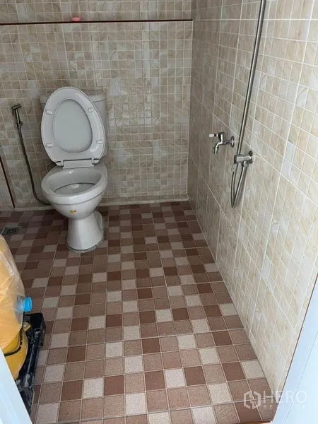 Warehouse for rent in Nonthaburi - Tiled bathroom with a Western toilet, handheld shower and wall taps inside the warehouse.