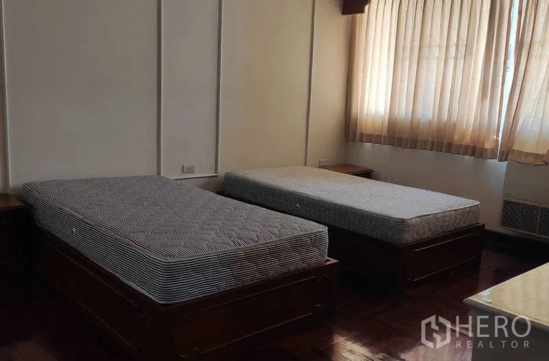 อพาร์ทเมนท์ ให้เช่าในKhlong Toei, Bangkok - ห้องนอนรองมีเตียงเดี่ยวสองเตียงและหน้าต่างผ้าม่านบานใหญ่