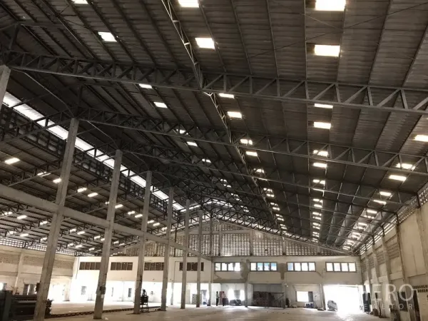 Warehouse for rent in Phra Pradaeng, Samut Prakan - Large warehouse interior with high steel truss roof, skylights and concrete floor.