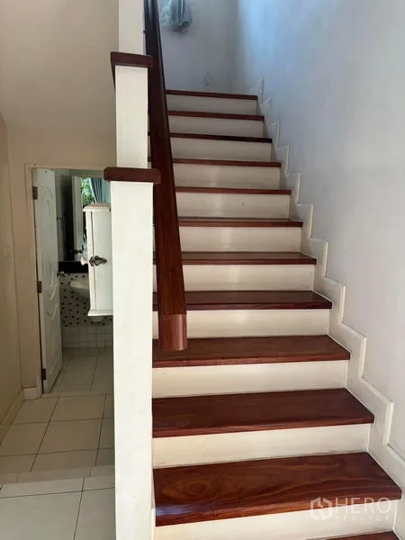 Detached House for rent in Bang Phli, Samut Prakan - Wooden staircase with white risers leading upstairs, bathroom beneath the stairs.