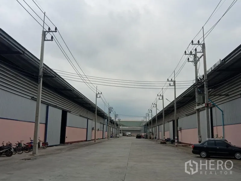 Factory for rent in Ban Phaeo, Samut Sakhon - Central avenue of the industrial compound lined with large sliding doors and parking bays.