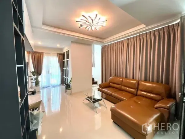 บ้าน ขายในBang Sao Thong, Samut Prakan - ห้องนั่งเล่นสว่าง โซฟาหนังตัวแอล ผ้าม่านยาว และโคมไฟดีไซน์