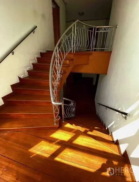 独立式住宅 出售在Prawet, Bangkok - 阳光照射的弧形木楼梯，金属扶手