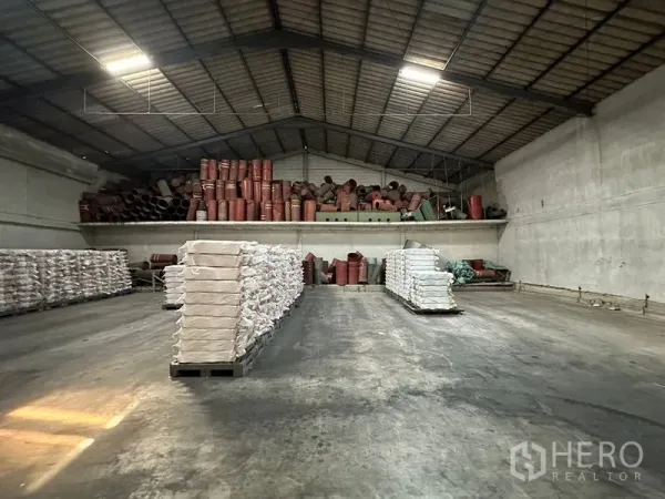Warehouse for rent in Lat Krabang, Bangkok - Spacious warehouse interior with concrete floor, high ceiling and mezzanine storage stacked with materials.