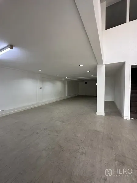 店屋 出租在Bang Na, Bangkok - 一层开放式空间，白墙、嵌灯与瓷砖地面，适合展示或零售。