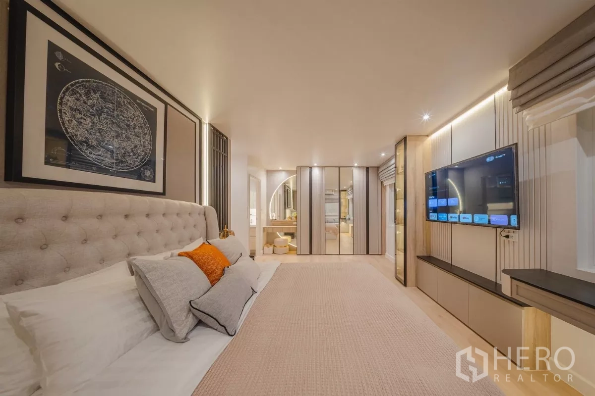 Condominium for rent in Yan Nawa, Bangkok - Spacious master bedroom with tufted headboard, mirrored wardrobes, TV wall and vanity.