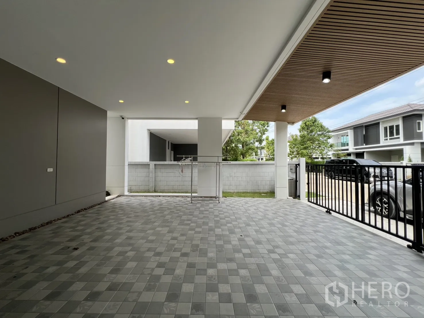 Detached House for rent in Lat Krabang, Bangkok - Spacious tiled carport facing the rear wall with neighboring modern houses visible.