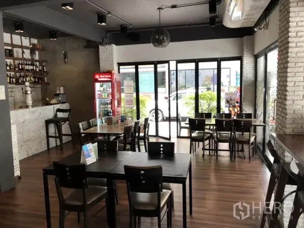 店屋 出租在Ratchathewi, Bangkok - 一楼用餐区，设大理石吧台、可折叠玻璃门与木质餐桌，面向街边绿化
