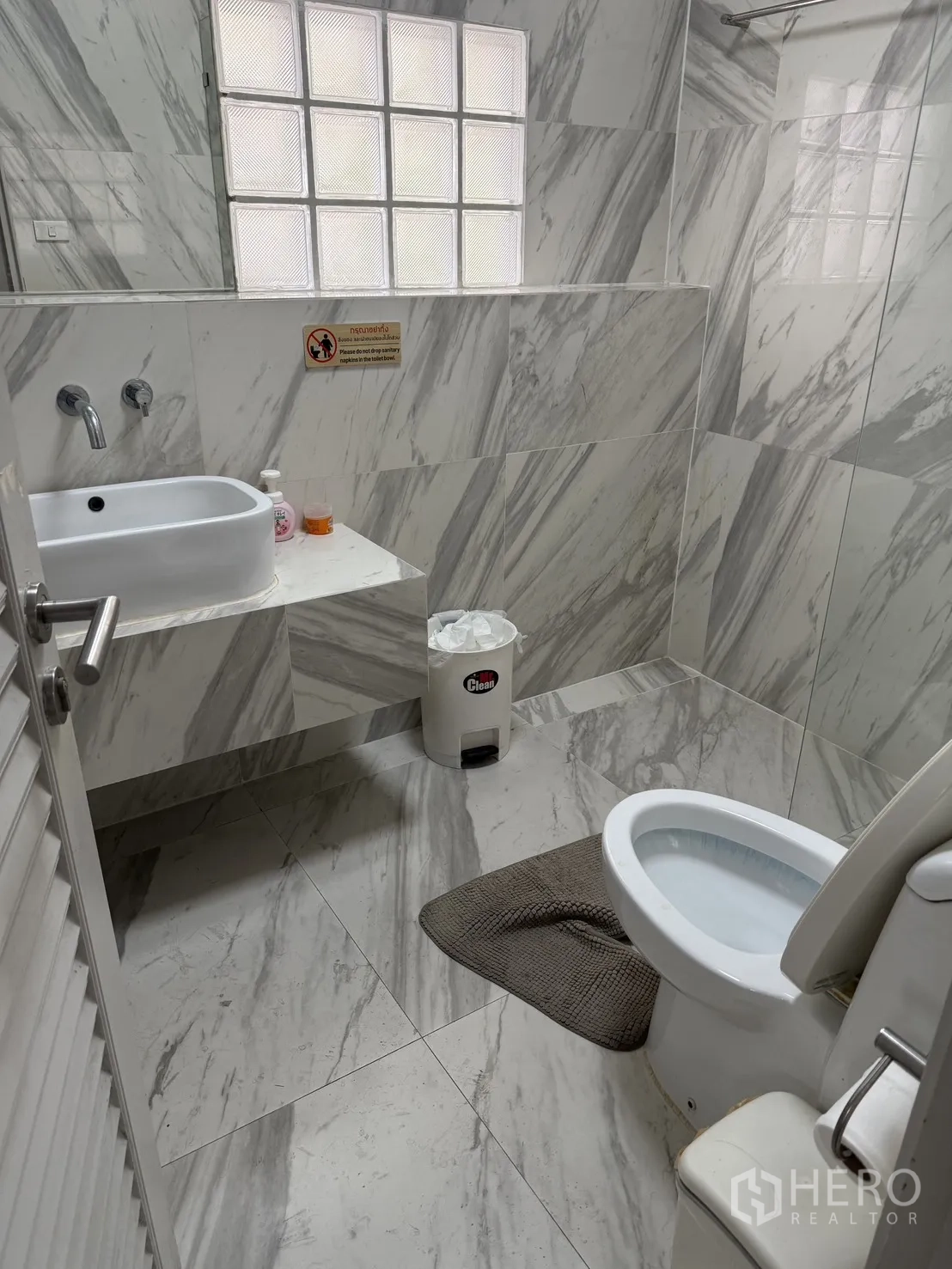 家庭办公室 for rent in Watthana, Bangkok - 浴室铺大理石纹瓷砖，玻璃砖窗，壁挂洗手盆与坐便器。