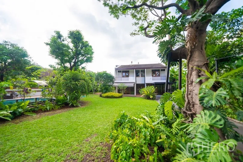 Detached House for rent in Huai Khwang, Bangkok - Expansive landscaped garden with large lawn and two-storey home in the background.