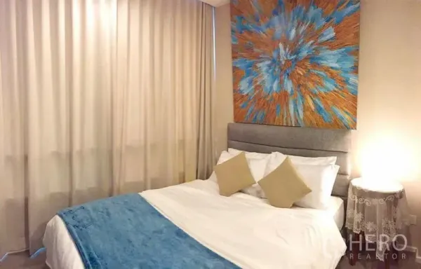 公寓 出租或出售在Watthana, Bangkok - 静雅卧室，长窗帘、床头灯，以及色彩抽象画。