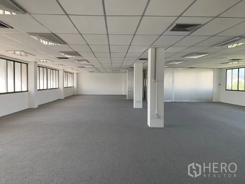 Office Space for rent in Bang Kapi, Bangkok - Spacious open-plan office floor with carpeted flooring, grid ceiling, air-conditioning vents and long rows of windows providing natural light in Bang Kapi, Bangkok.