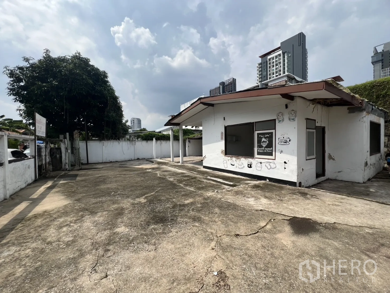 独立式住宅 出租在Phra Khanong, Bangkok - 房屋正面视角，白色小屋配超大混凝土车道与围墙庭院。