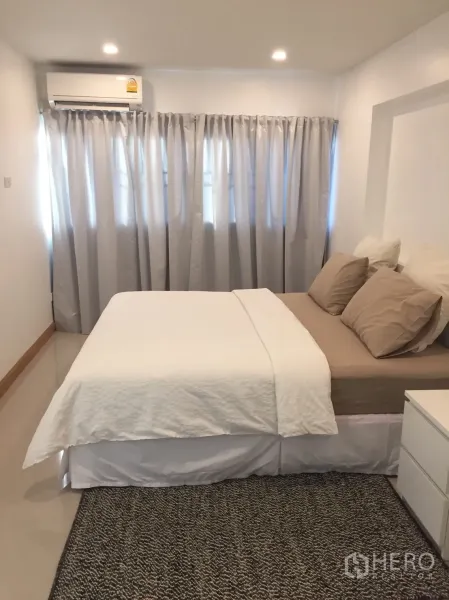 Condominium for rent in Watthana, Bangkok - Cozy bedroom with double bed, neutral linens, recessed lighting, air conditioner, and full-length curtains.