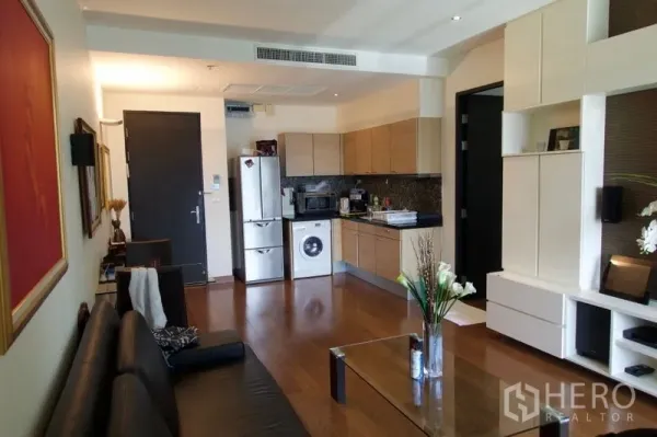 公寓 出售在Pathum Wan, Bangkok - 开放式客厅，木地板，带内置收纳与紧凑厨房，配洗衣机和冰箱。