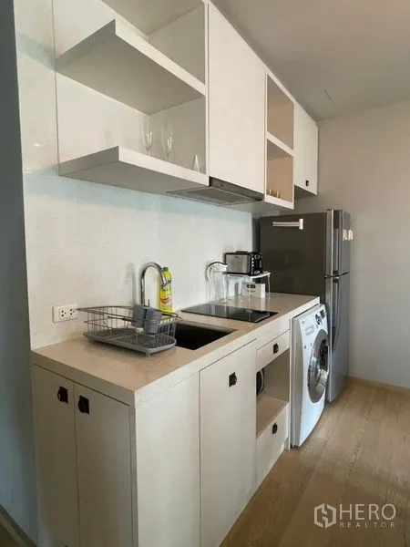 คอนโด ให้เช่าในBangkok - ครัวแนวตรงมีซิงก์ เตา ตู้ชั้นลอย ตู้เย็น และเครื่องซักผ้า