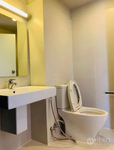 Home Office for rent - Modern bathroom with white sanitary ware, wall mirror and light-colored tiles.