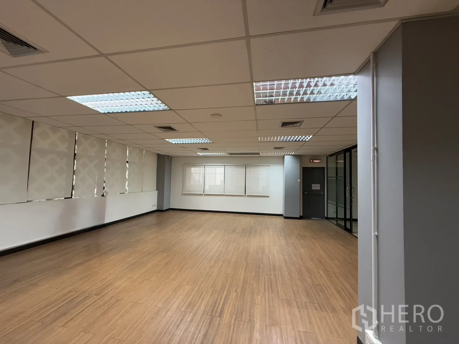 办公空间 出租 - 宽敞开放区，连续窗带卷帘与木纹地板。