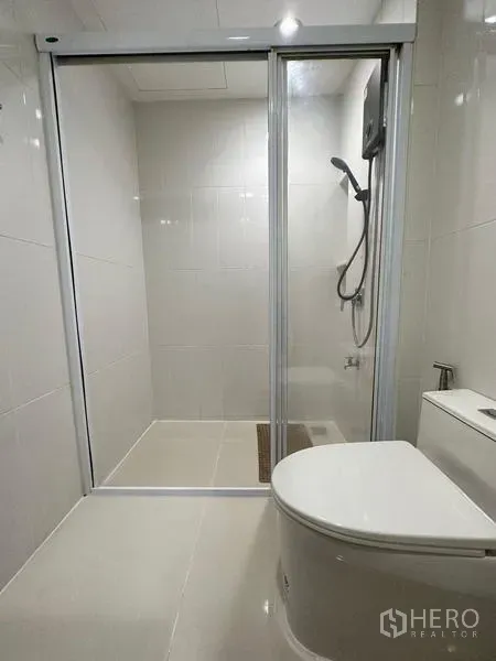 Townhouse for rent in Chom Thong, Bangkok - Shower room with sliding glass enclosure, handheld shower and toilet.