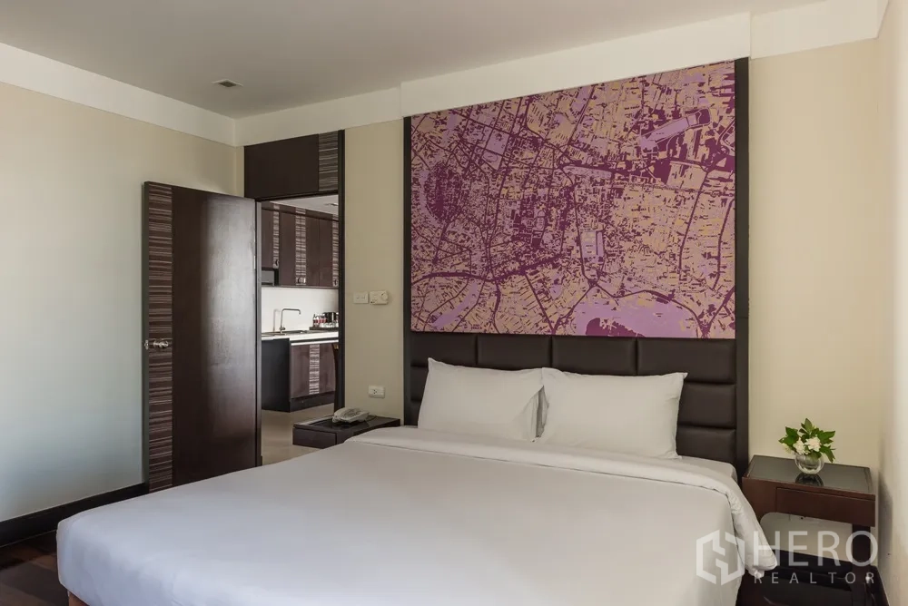 อพาร์ทเมนท์ ให้เช่าในKhlong Toei, Bangkok - มุมห้องนอนหลักเชื่อมต่อครัวย่อม พร้อมพนักหัวเตียงบุนวมและโต๊ะข้าง